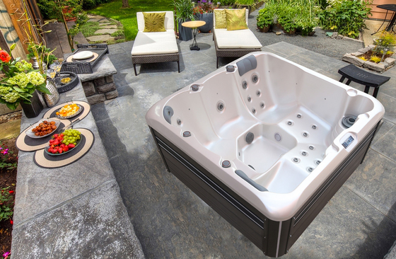Une baignoire en plein air en acrylique, une baignoire de massage en jacuzzi avec cascade et des lumières colorées.